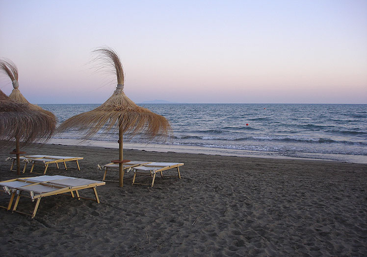 Spiaggia del Fuorirotta Beach Club al tramonto con ombrelloni in silhouette